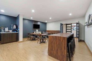 A modern kitchen with a wooden island, built-in appliances, and a seating area with tables and chairs. - Villa Inn & Suites, SureStay Collection by Best Western (Hearst)
