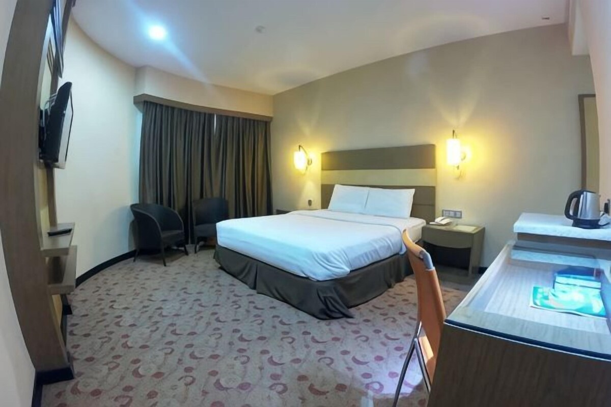 A hotel room with a bed, desk, chair, and a minibar.