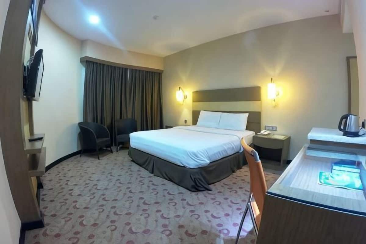 A hotel room with a bed, desk, chair, and a minibar.