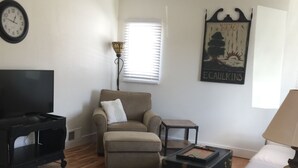 Un salon comprenant un canapé, un fauteuil, un meuble pour la télévision et un tapis décoratif.