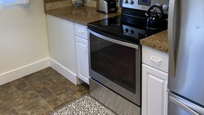 Une cuisine moderne avec des meubles blancs, un réfrigérateur en acier inoxydable, un four à micro-ondes, une cuisinière et un grille-pain.