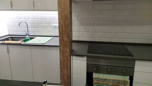 A kitchen with a sink, a stove, and a tiled backsplash. - D&N Hospedagem - Hostel (Lisbon)