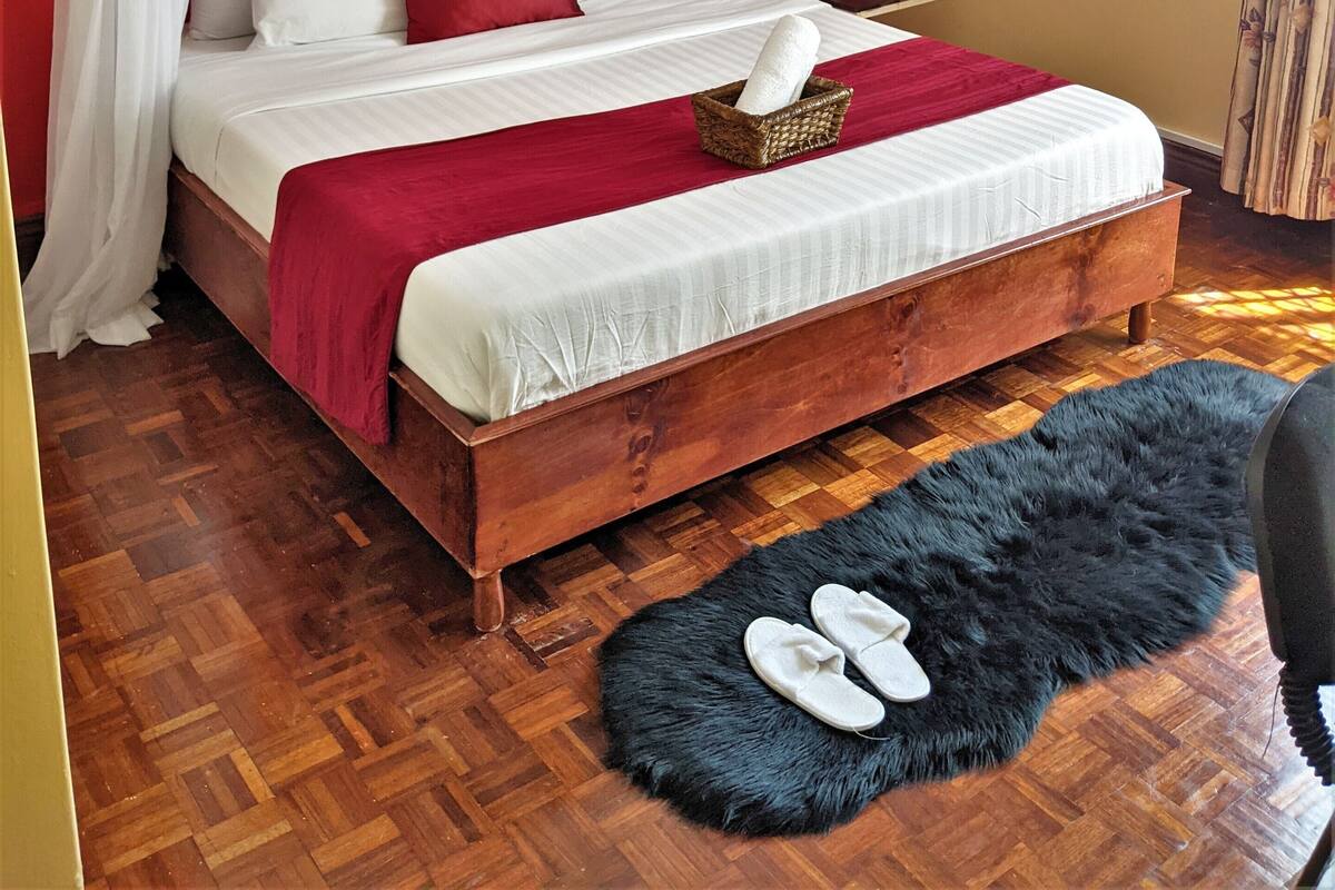 Ein Schlafzimmer mit einem hölzernen Bett, roten Wänden, weißer Bettwäsche und einem Baldachin.