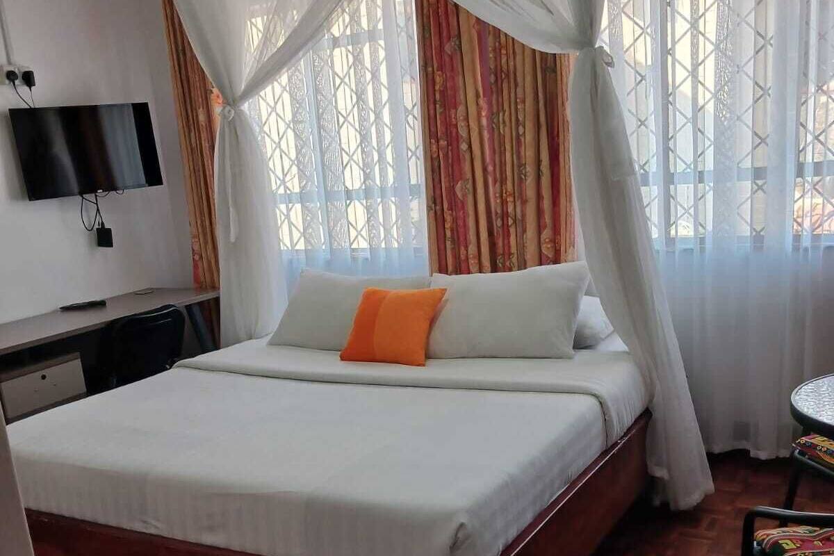 Ein Schlafzimmer mit einem Bett, einem Schreibtisch, einem Sessel und einem Fernseher.