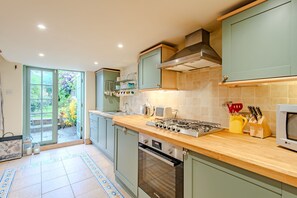 A kitchen with a stove, oven, and microwave. - Charming, period cottage located just off the vibrant  high street of Deal with a gorgeous garden! (Deal)