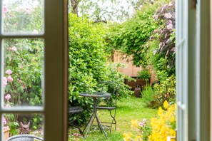 A garden with a table and chair, a wooden bench, and a statue. - Charming, period cottage located just off the vibrant  high street of Deal with a gorgeous garden! (Deal)