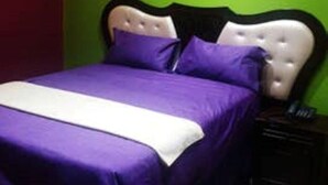 A bed with a white headboard and purple bedding in a room with green walls. - B & B - Pretoria La Vie (Booysens)