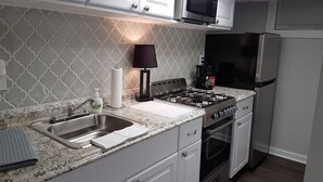 A modern kitchen with a stainless steel sink, a gas stove, a microwave, and a refrigerator. - The Filly - 6 miles to Churchill Downs - Pets - Highlands/Cherokee Triangle (Louisville)