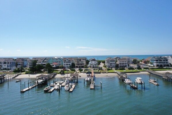 A marina with boats docked, a pier, and residential buildings in the background.