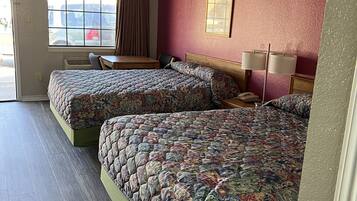 A hotel room with two beds, a window with curtains, a desk, and a chair.
