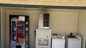 Máquina automática de vendas com publicidade da Pepsi, bebedouro e duas secadoras numa área externa coberta.