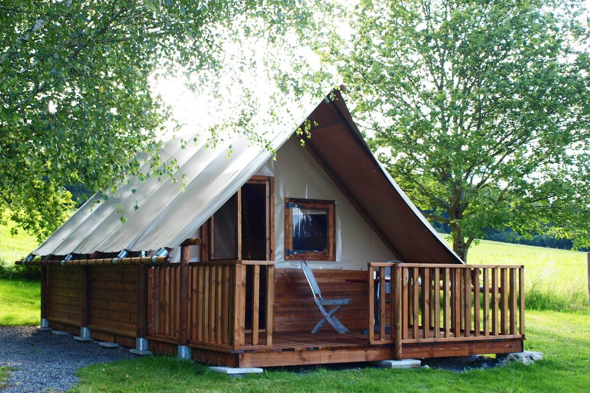 A wooden cabin with a sloped roof, a deck, and a window.