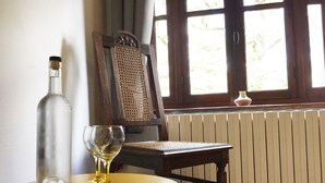 Een houten stoel met een gevlochten rugleuning, een ronde houten tafel en twee wijnglazen op de tafel.