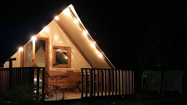 Een gezellig, chaletachtig huisje met een houten terras en een klein raam.