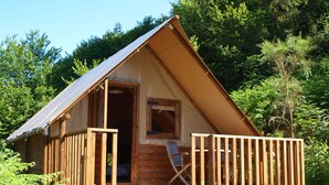 Een klein houten huisje met een veranda, een raam en een deur.
