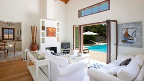 A modern living room with a pool view, white furniture, and a painting on the wall.
