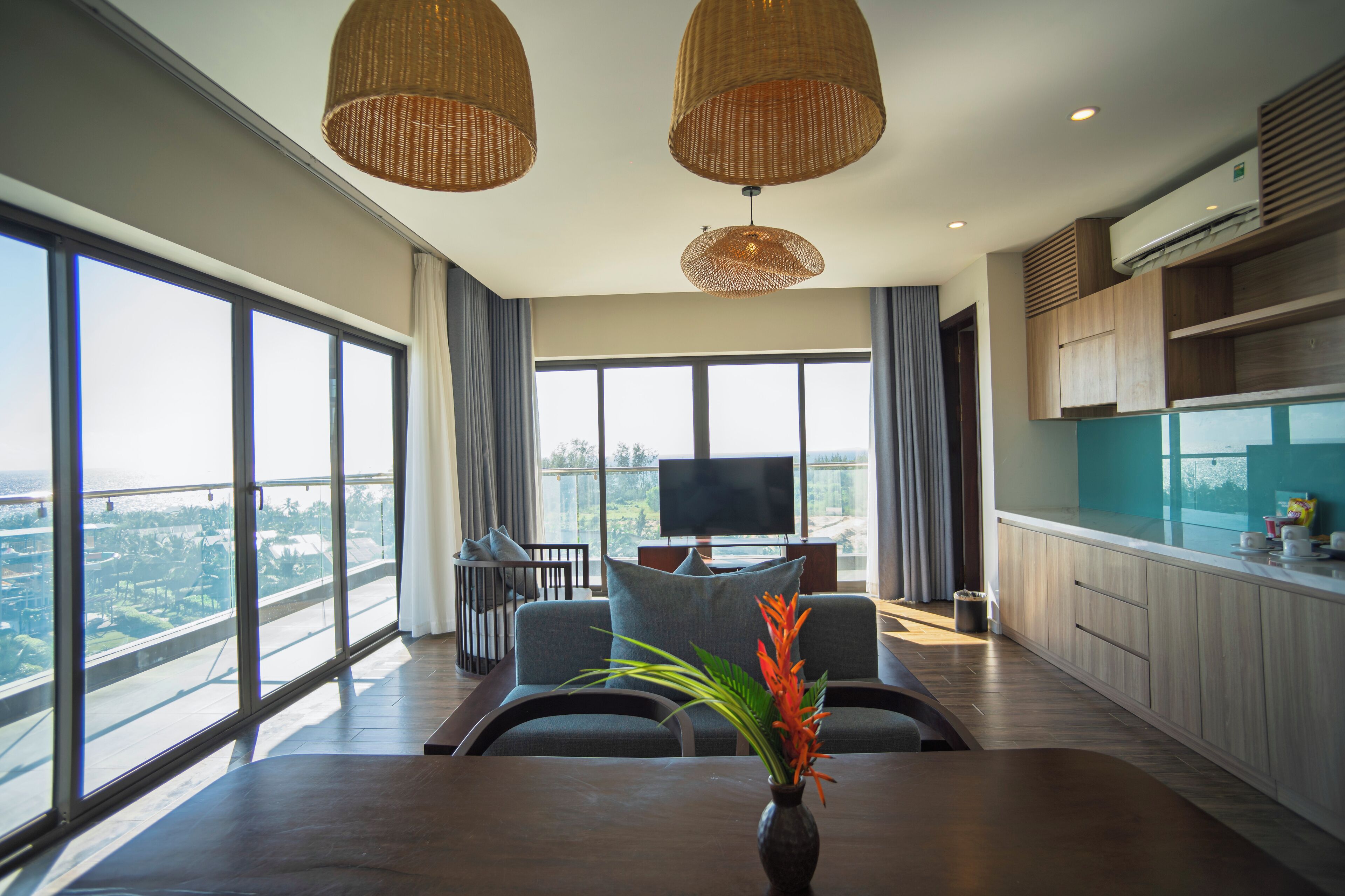 Een moderne woonkamer met grote ramen, een eethoek en een keuken.