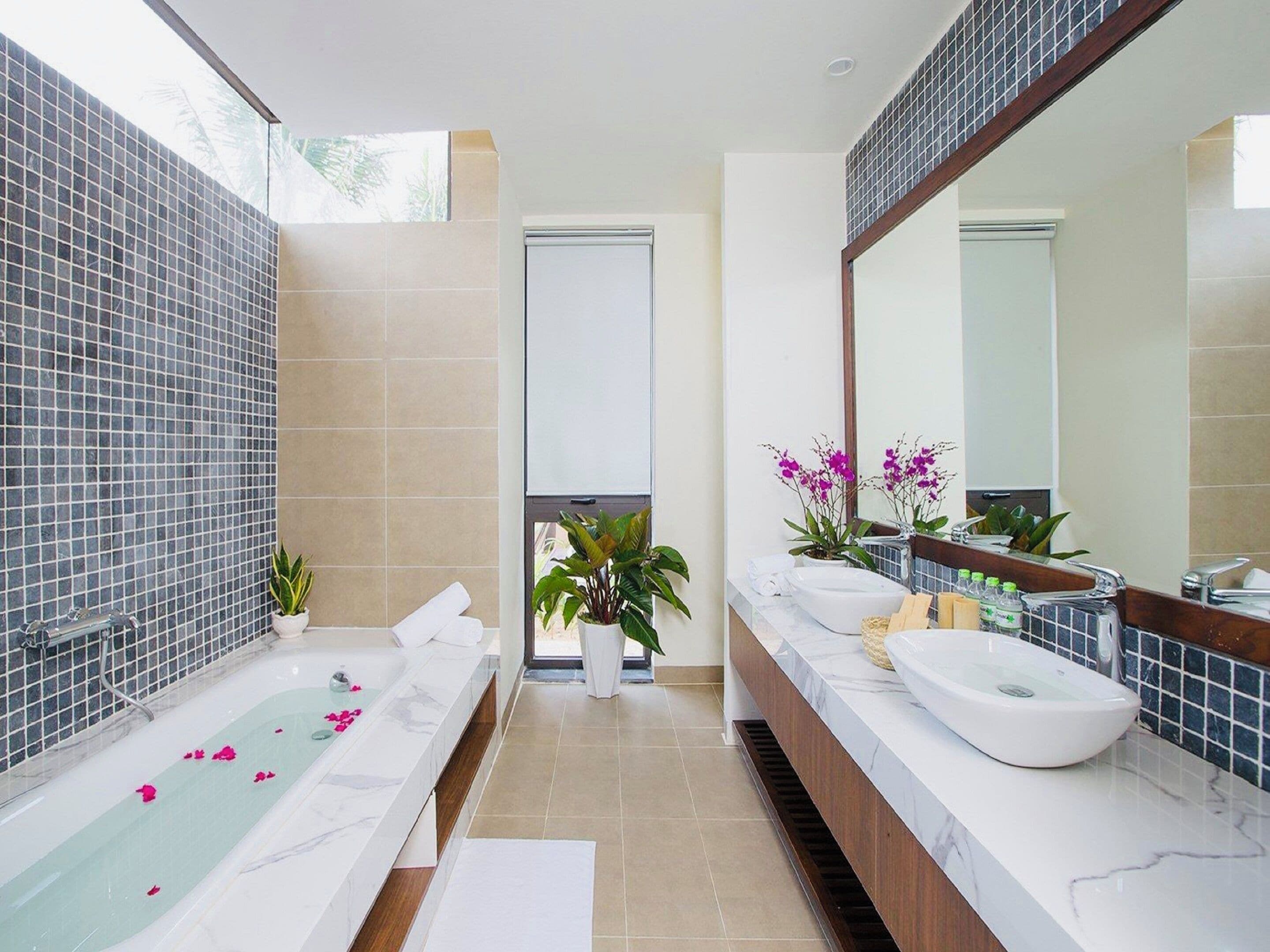 A modern bathroom with a bathtub, two sinks, and a large mirror.