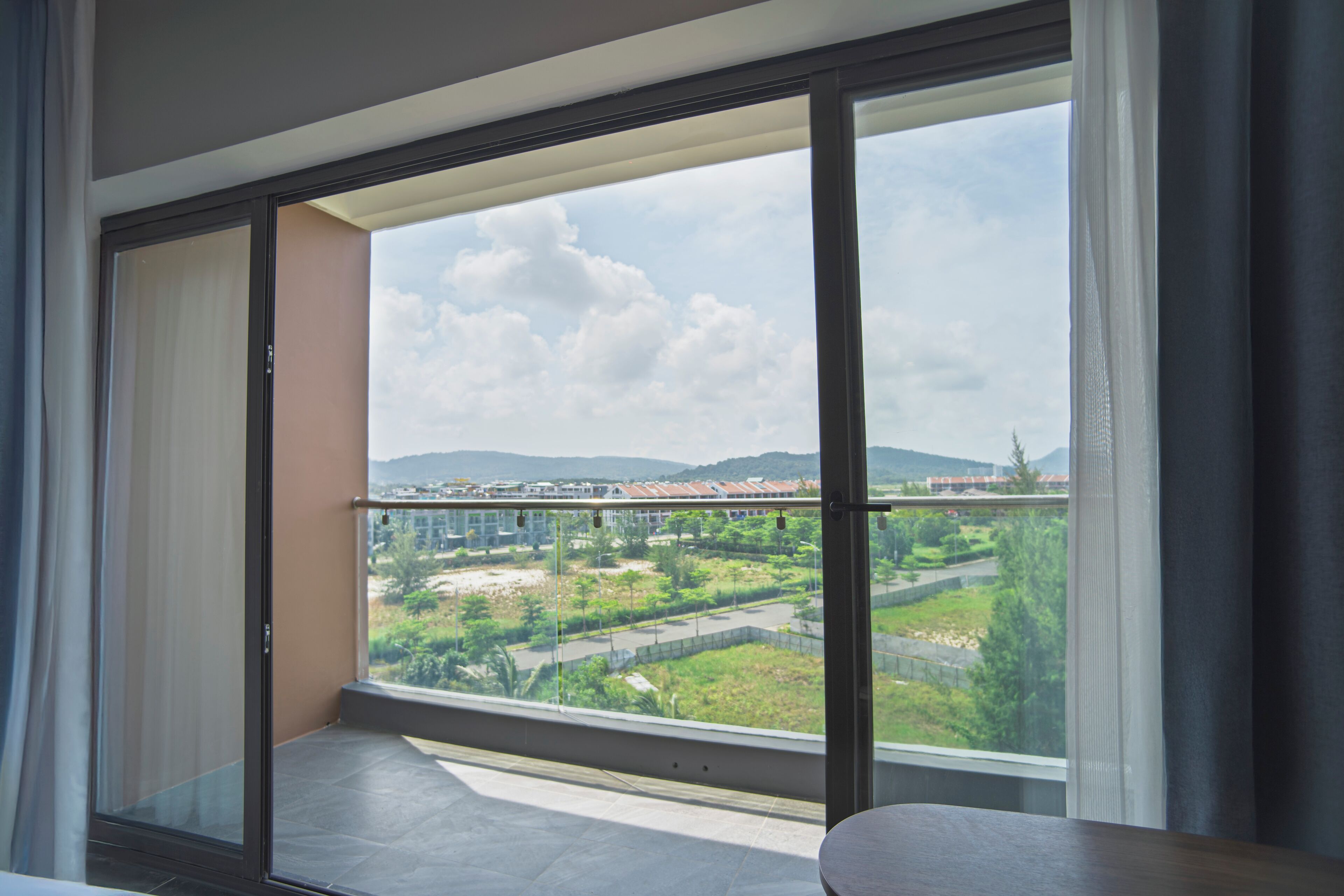 A balcony with a view of a cityscape, including buildings and greenery.