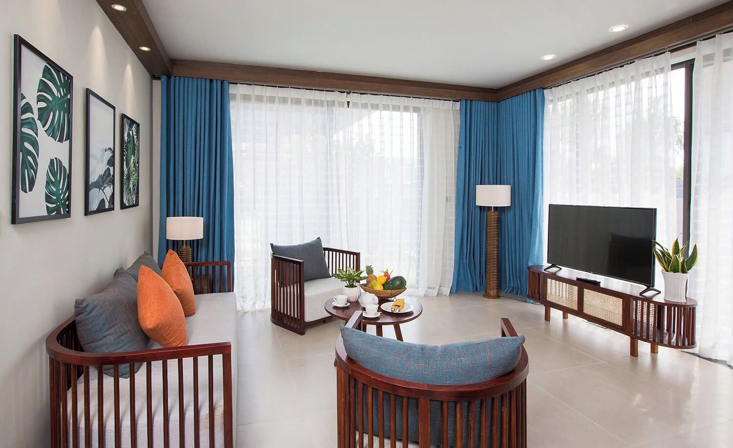 Een moderne woonkamer met een bank, fauteuils, een salontafel en een televisie.