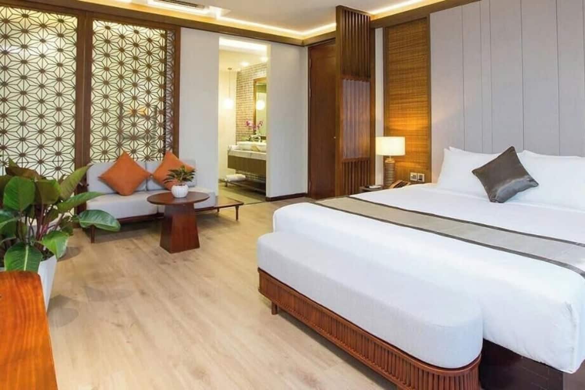 Une chambre d’hôtel avec un grand lit, un canapé, une petite table et un mur décoratif.