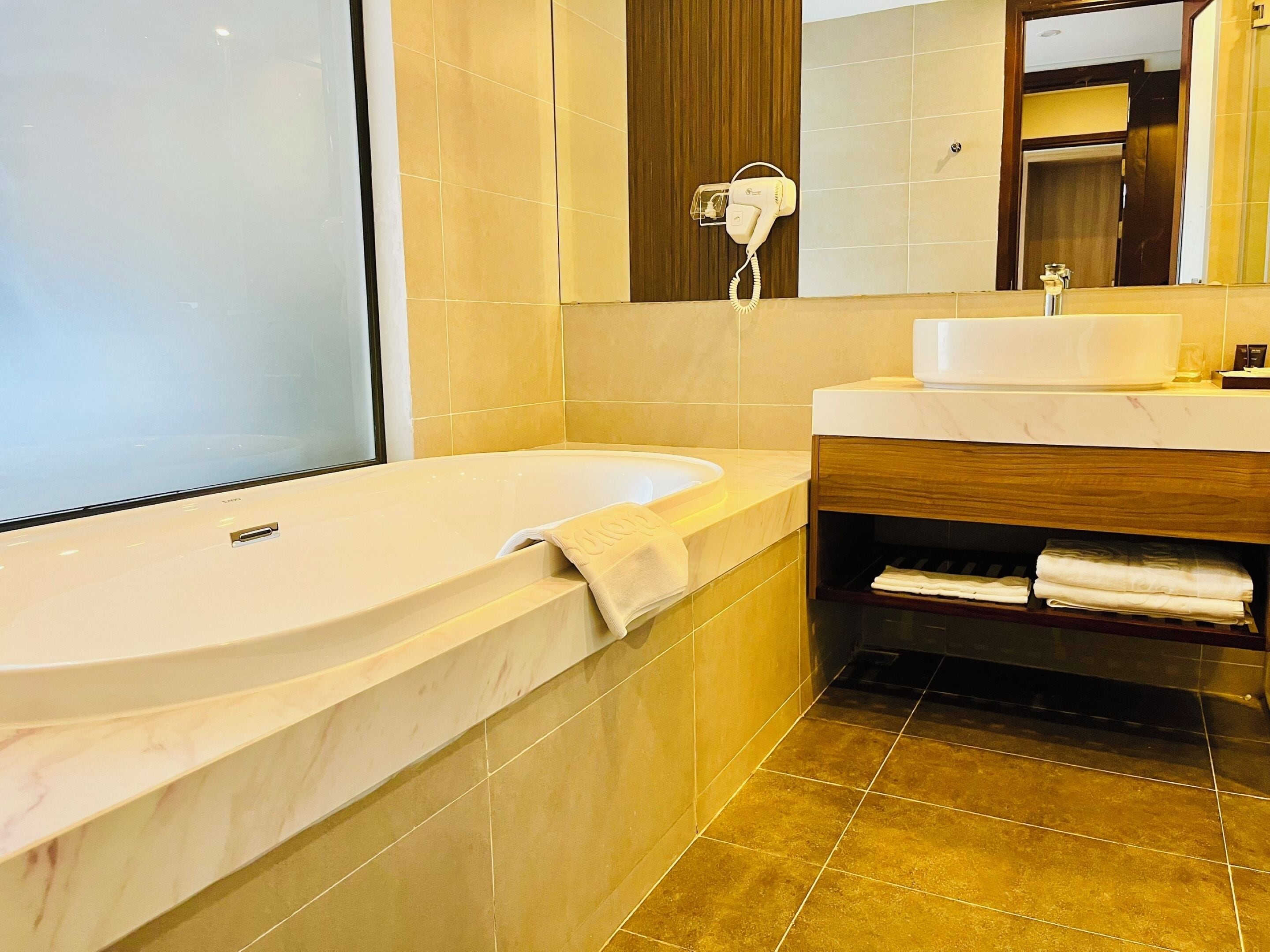 A modern bathroom with a large bathtub, a vanity with a mirror, and a towel rack.