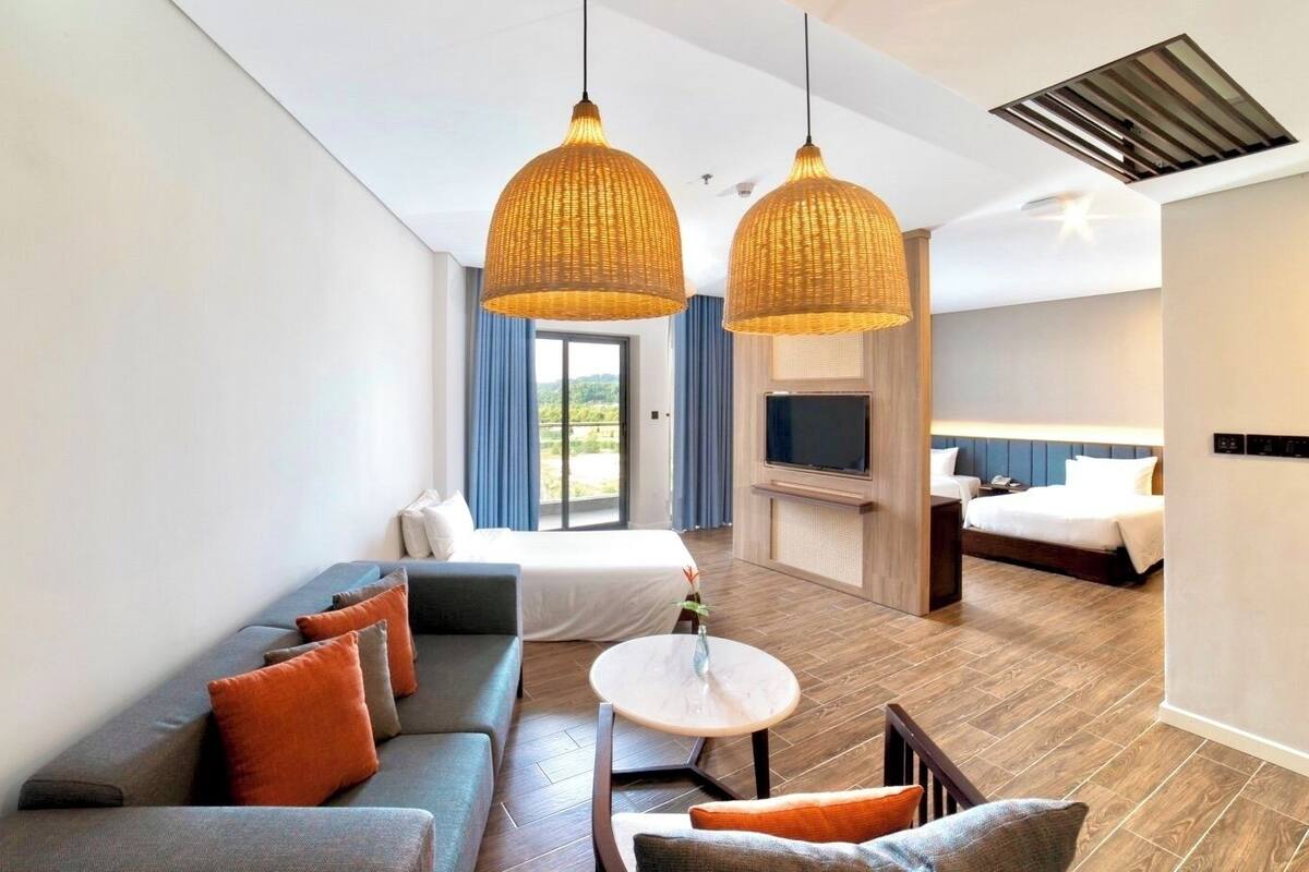 Une chambre d’hôtel moderne équipée d’un canapé, d’une table ronde, d’un lit et d’un téléviseur.