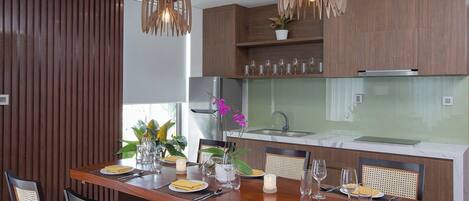 A modern kitchen with wooden cabinets, a marble countertop, and a dining area set with a wooden table and chairs.