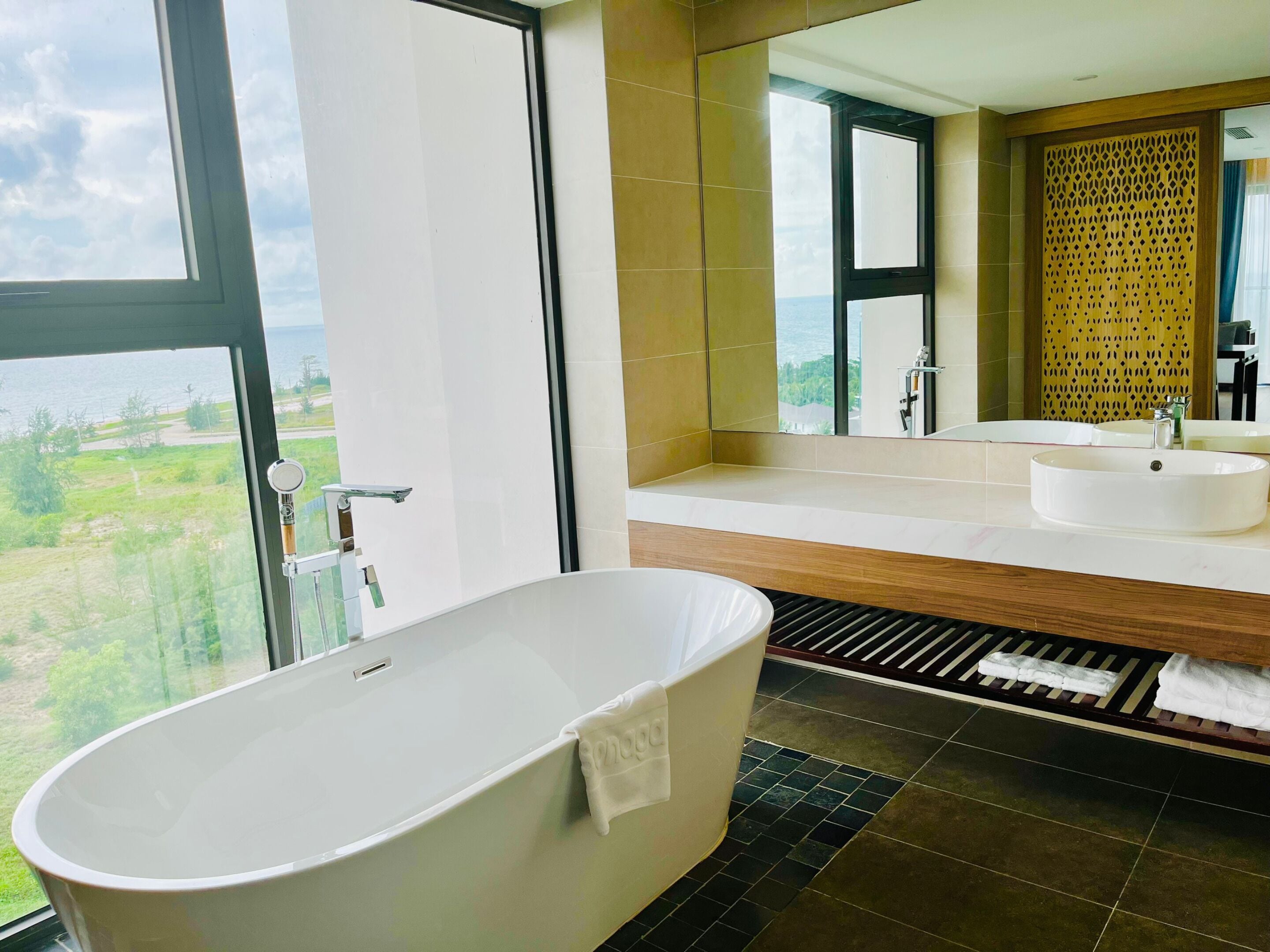 Une salle de bain moderne avec une baignoire sur pieds, un grand miroir et une vue sur l’extérieur.