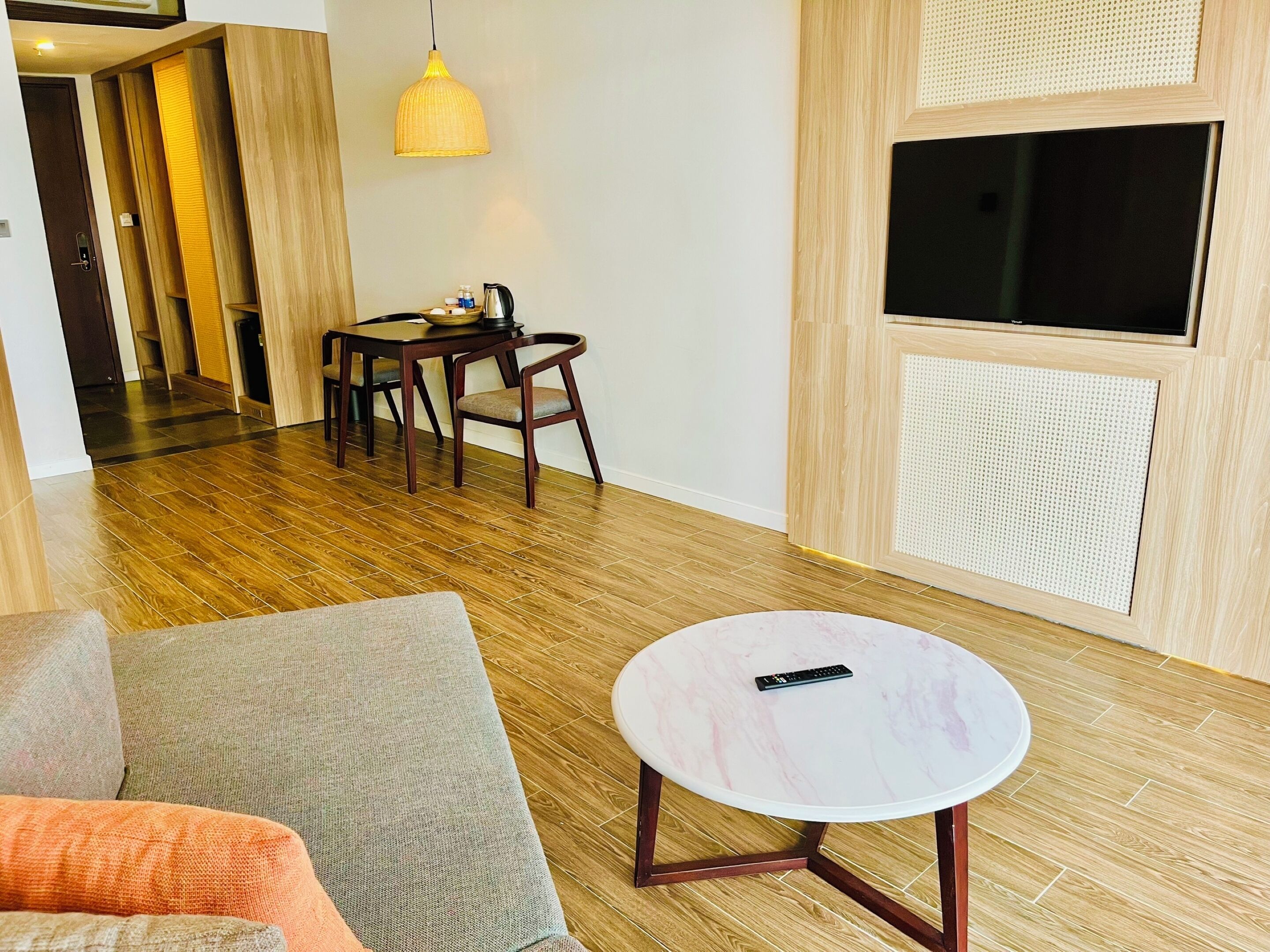 A modern living room with a wooden floor, a round marble table, a sofa, and a TV mounted on the wall.