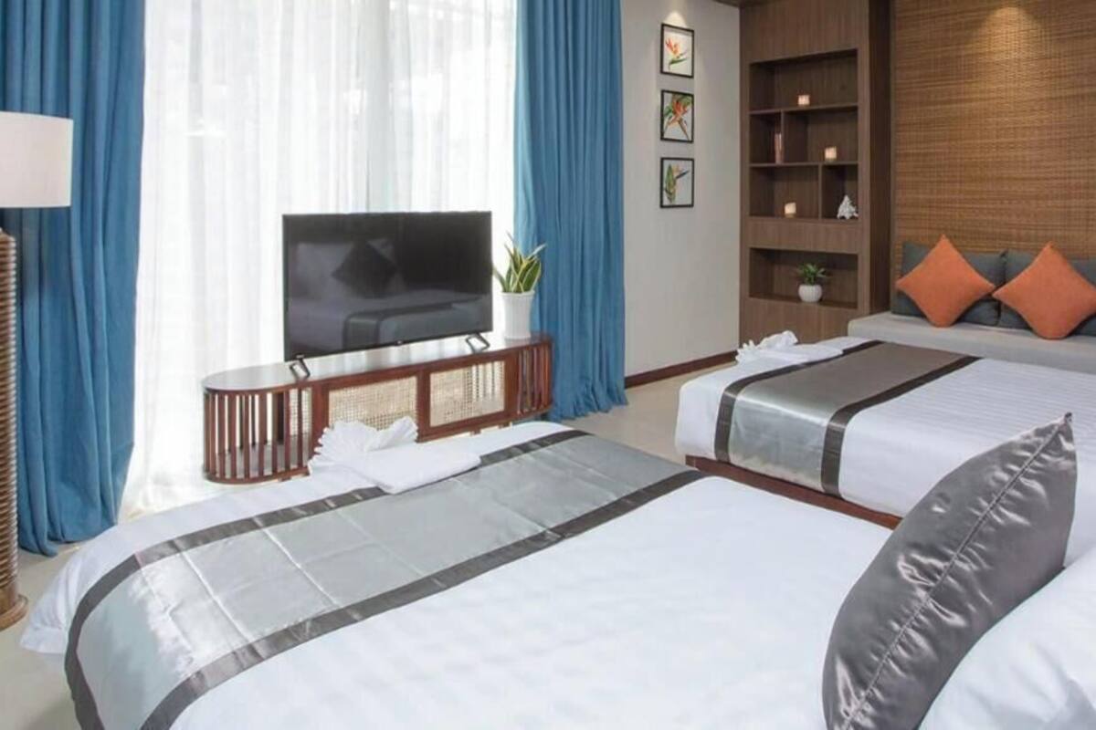 Une chambre d’hôtel avec deux lits, une télévision, un bureau et une bibliothèque.