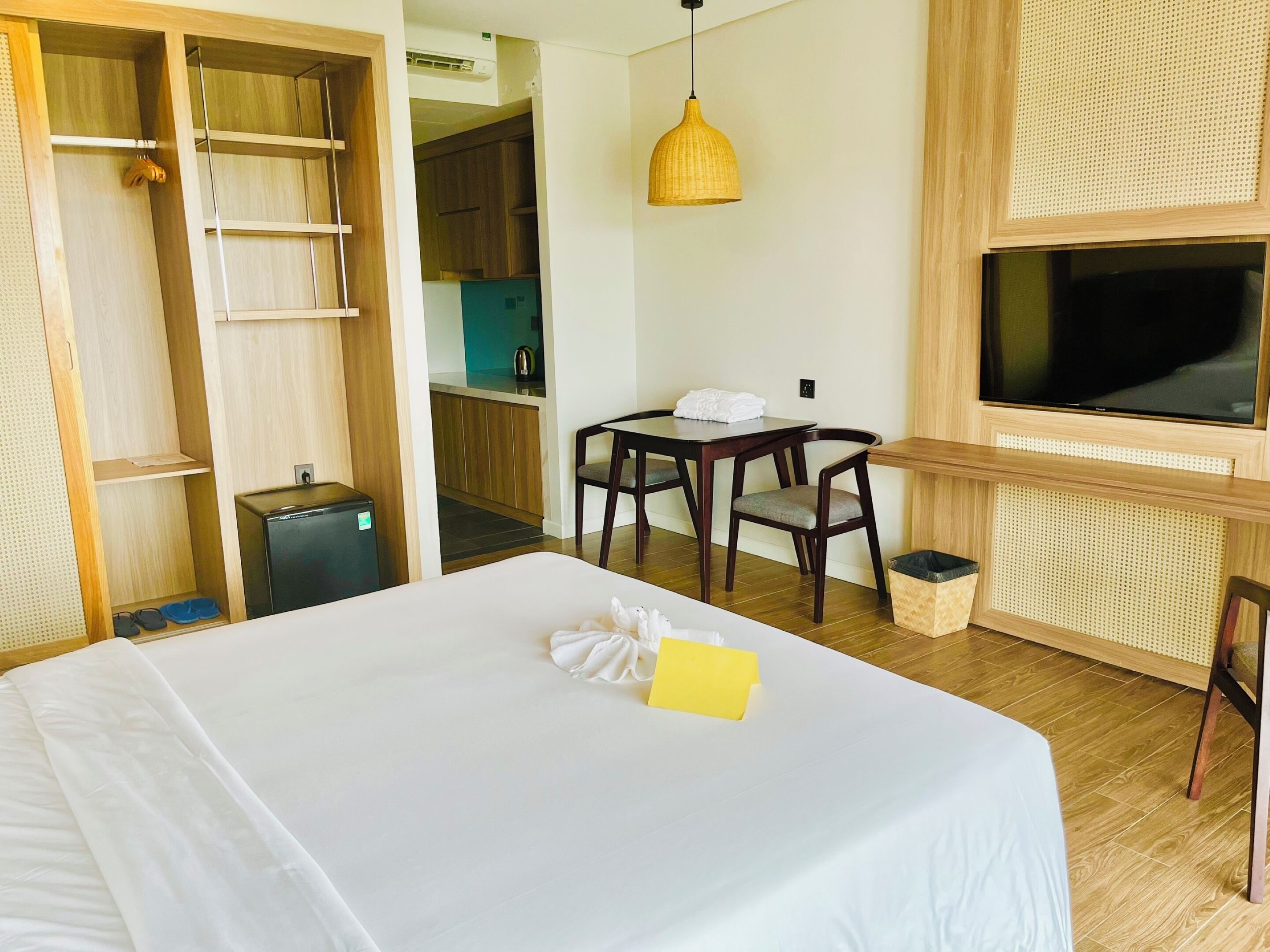 A hotel room with a bed, a desk with chairs, a television, and a wardrobe.
