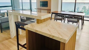 A modern kitchen with a marble countertop, wooden accents, and a large window overlooking the sea. - Sonaga Beach Resort & Villas Phu Quoc (Phu Quoc)