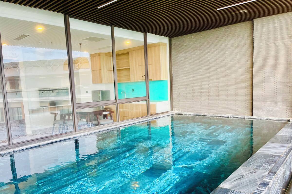Une piscine intérieure à l’eau claire, dotée de casiers en bois et d’un design de plafond moderne.