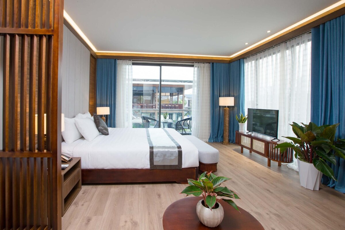 Une chambre d’hôtel avec un grand lit, une télévision, un bureau et une vue sur le balcon.