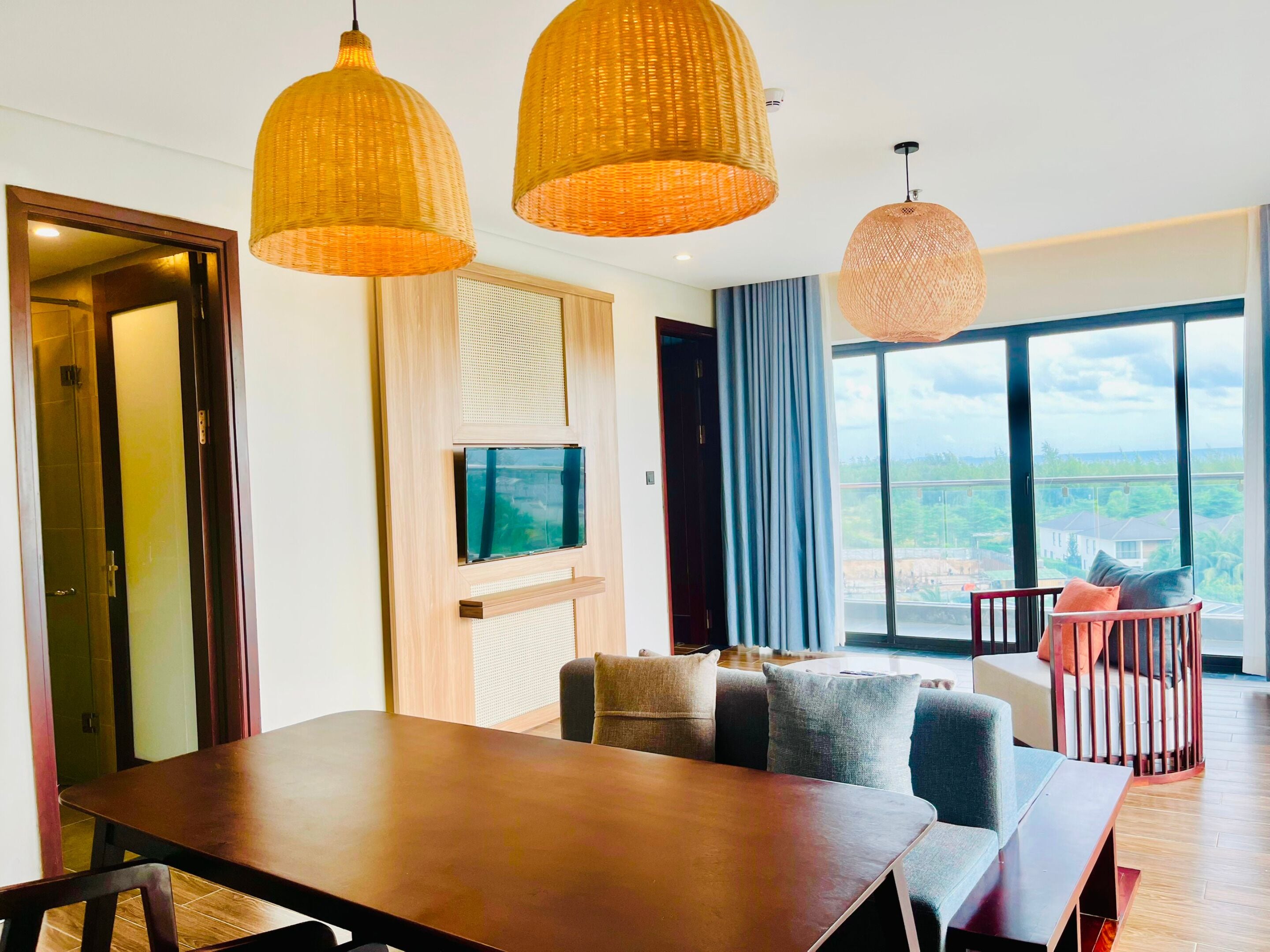 Un salon moderne avec une table à manger en bois, deux canapés et une grande fenêtre donnant sur la ville.