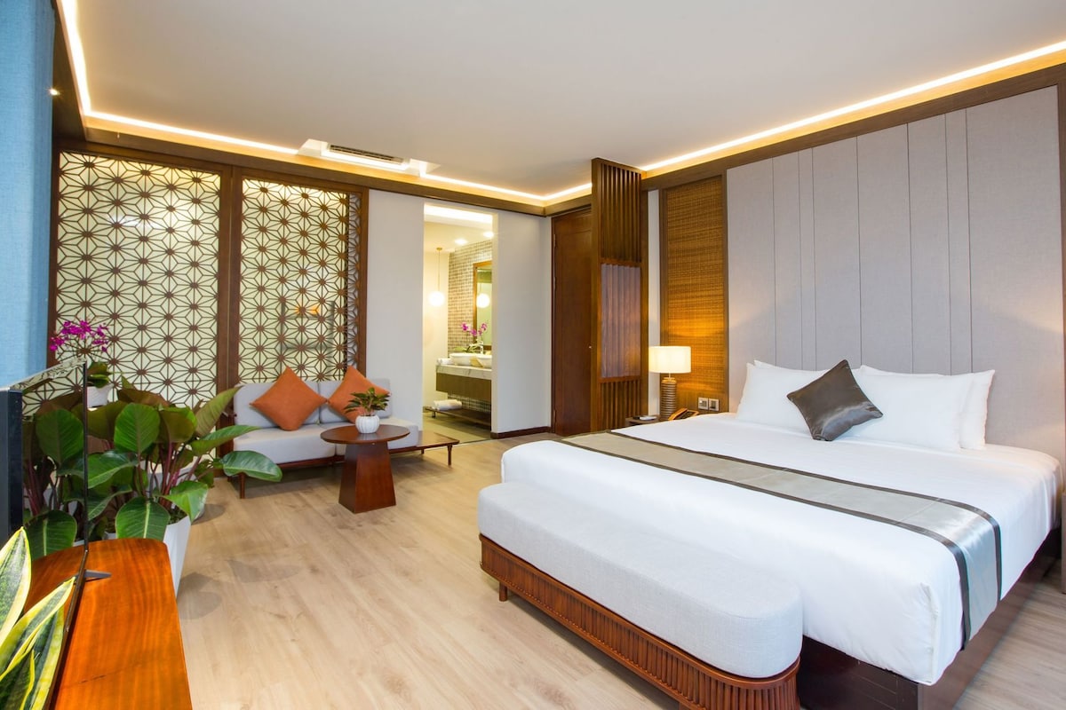 Une chambre d’hôtel moderne avec un grand lit, un canapé, une petite table et un mur décoratif.