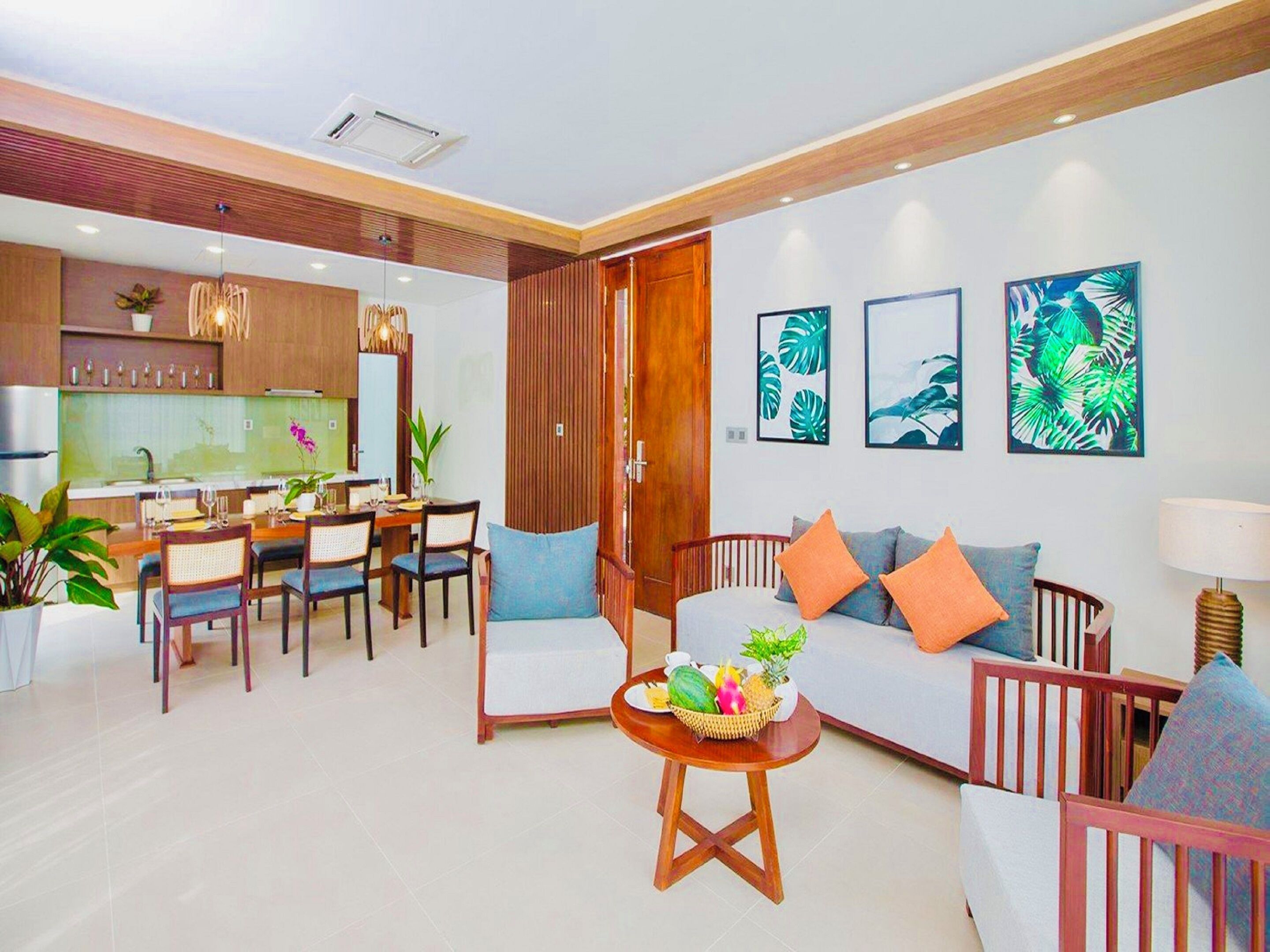 Una sala moderna con un sofá, sillas, un comedor con una mesa y una cocina al fondo.