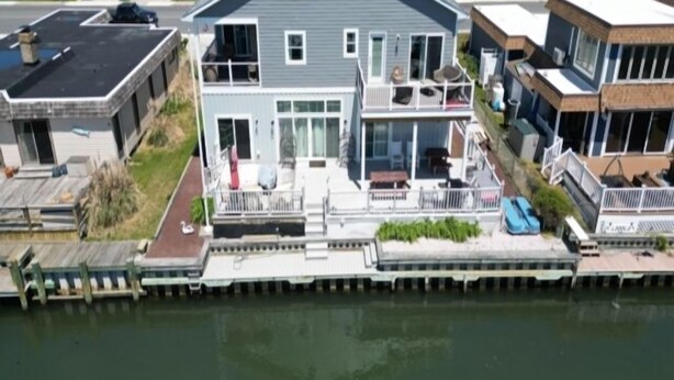 Una casa de dos pisos con un muelle, un balcón y un porche delantero.