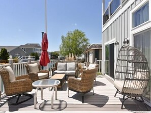 Eine Terrasse mit Korbmöbeln, einem Glastisch und einem roten Sonnenschirm.