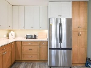 A kitchen with wooden cabinets, a stainless steel refrigerator, a microwave, and a toaster.