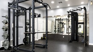 Ein Fitnessraum mit Squat-Rack, Gewichte und einer Hantelbank.