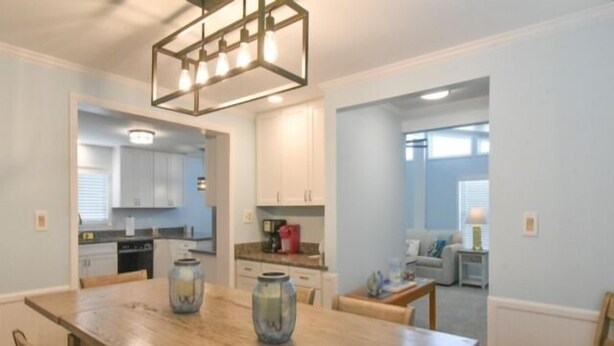 A dining area with a wooden table, chairs, and a kitchen in the background.