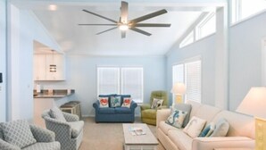 A spacious living room with a ceiling fan, a sofa, a coffee table, and a small side table.