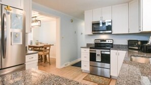 A modern kitchen with white cabinets, stainless steel appliances, and granite countertops.