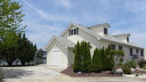 A single-story house with a garage, a sloped roof, and a front yard with landscaping. - Montego Bay Community Canal Front  wrap around porch, boat tie up, Pools, Tennis N. Ocean City MD! (Ocean City)