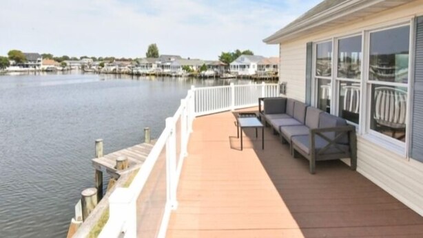 A waterfront property with a covered deck, outdoor seating, and a view of the water and neighboring houses. - Montego Bay Community Canal Front  wrap around porch, boat tie up, Pools, Tennis N. Ocean City MD! (Ocean City)