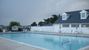 A swimming pool with lounge chairs and a covered area. - Montego Bay Community Canal Front  wrap around porch, boat tie up, Pools, Tennis N. Ocean City MD! (Ocean City)