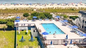 Un complexe hôtelier doté d’une piscine, de chaises longues et offrant une vue sur la plage.