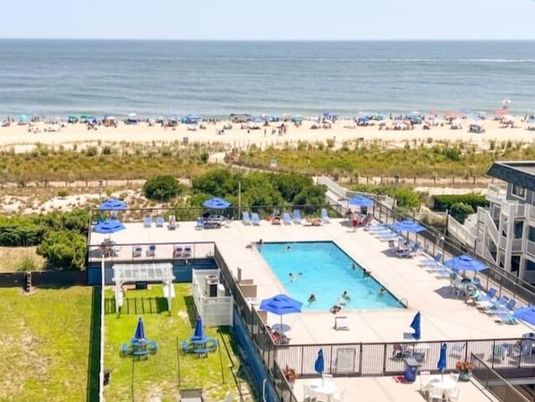 Un complexe hôtelier doté d’une piscine, de chaises longues et offrant une vue sur la plage.